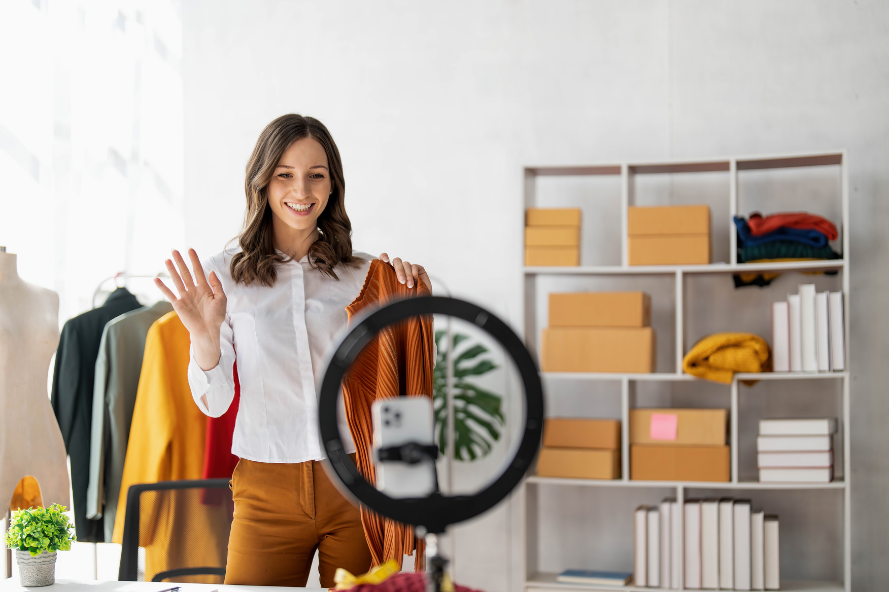 Mulher gravando vídeo de moda com ring light mostrando look para redes sociais.