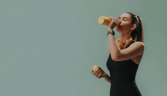 Mulher usando macaquinho fitness verde durante treino em estúdio.