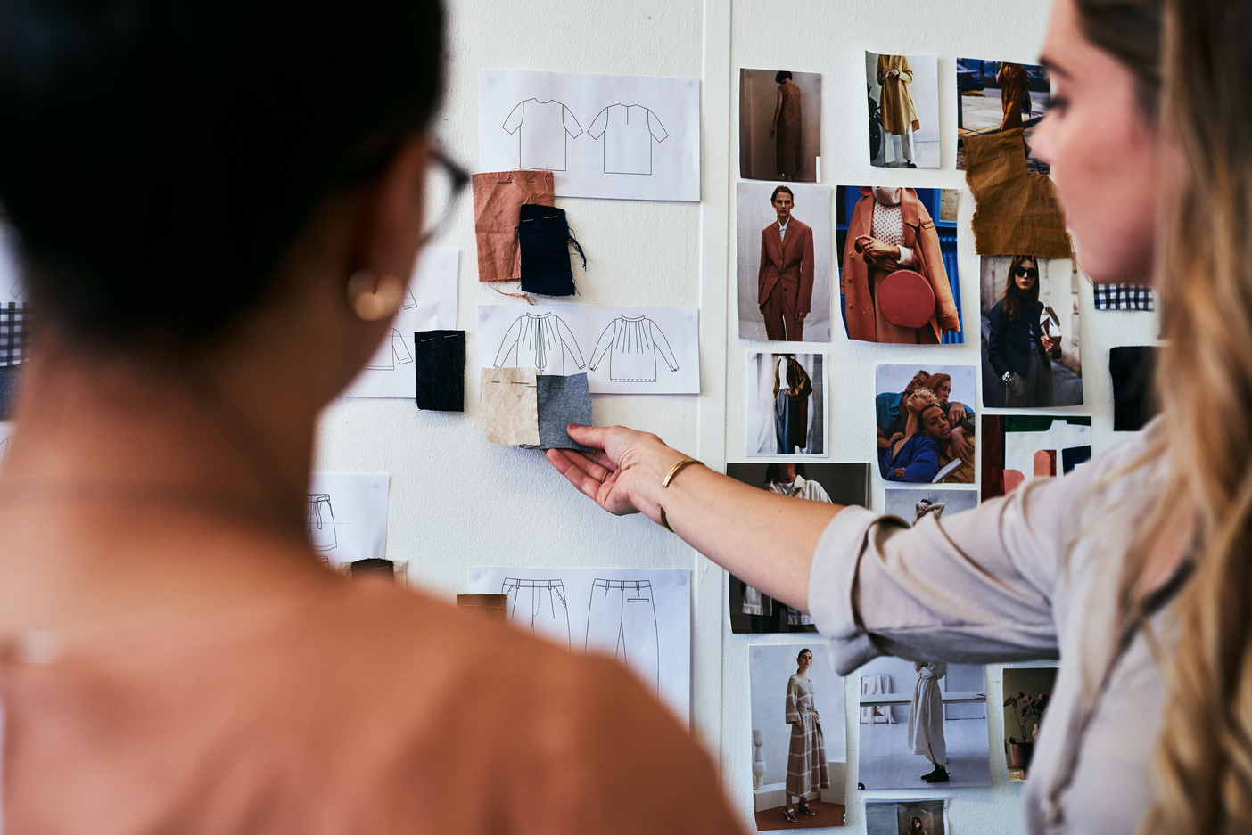 Equipe de moda analisando referências, tecidos e modelagens para coleção feminina funcional.